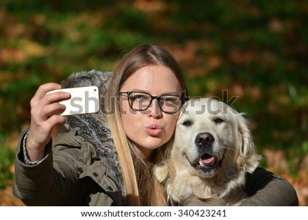Young girl with spectacles posing and taking selfie with her golden retriever dog