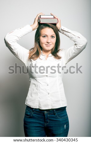 Student girl with books on the head. office manager. studio photo on a gray background
