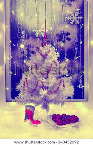 
Christmas tree with toys and a garland on a blue field with snowflakes and glowing lights, retro, old style picture