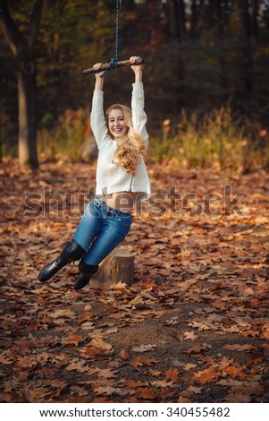Two happy and cheerful young girl students, blond and brunette in coat and jeans laughing in sunny autumn park full of fallen leaves, horizontal pictures