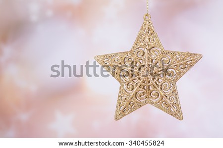 Hanging gold Christmas star ornament with a colorful holiday background