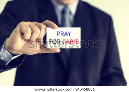 Businessman holding card with pray for paris message,vintage color.
