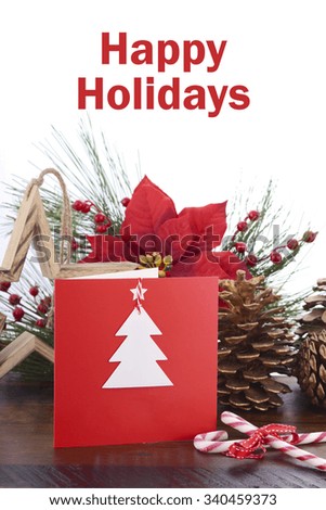 Handmade Christmas greeting card using cutout shapes on natural kraft paper on vintage wood table with festive decorations.