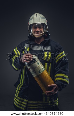 Firefighter rescue holds yellow oxygen tank. Isolated on grey background.