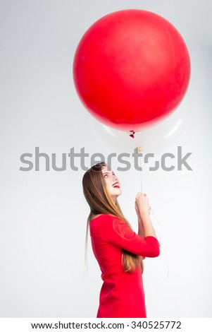Portrait of a cheerful woman in red dress holding balloons isolated on a white background