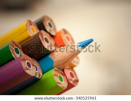 Pack of color pencils with a single sharp one symbolizing leadership concept and unique approach by standing out of the crowd group elements