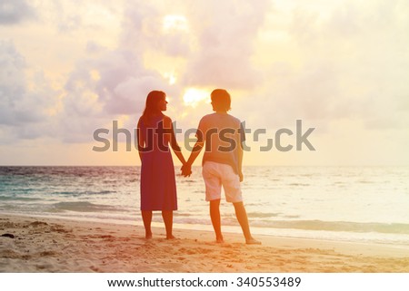 Happy young romantic couple on the beach at sunset