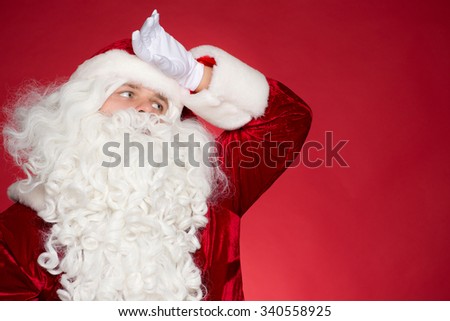 Worker of the Year. Tired Father Christmas wipes his forehead with his hand looking exhausted towards blank copyspace