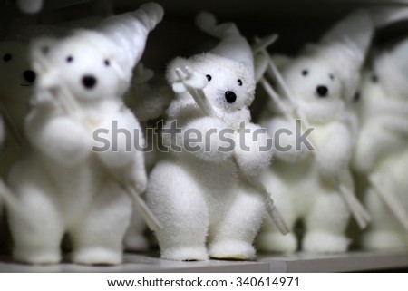 Closeup view of many little cute fluffy white figures of white bears in hat and scarfs holding ski poles, horizontal picture