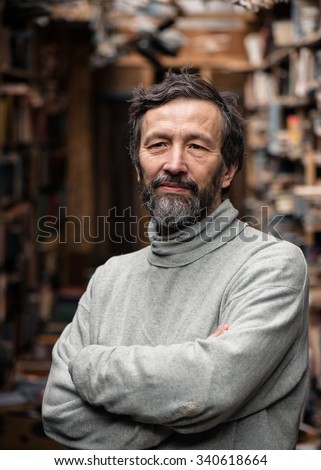 Portrait of authentic senior man with standing with crossed hands on book market