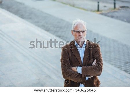 adult person with gray hair and eyeglasses elegant dressed, outside on the steps of an office building