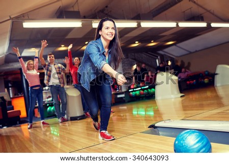 people, leisure, sport and entertainment concept - happy young woman throwing ball in bowling club