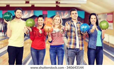 people, leisure, sport, friendship and entertainment concept - happy friends holding balls and showing thumbs up in bowling club