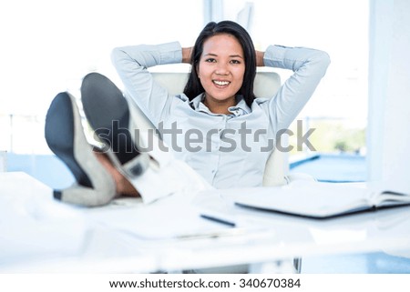 Smiling businesswoman relaxing herself at the desk in work