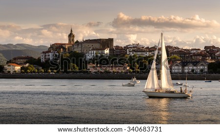 A sailing ship returns to port at sunset