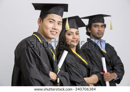 Group of Indian college graduates wearing cap and gown holding diploma on white background