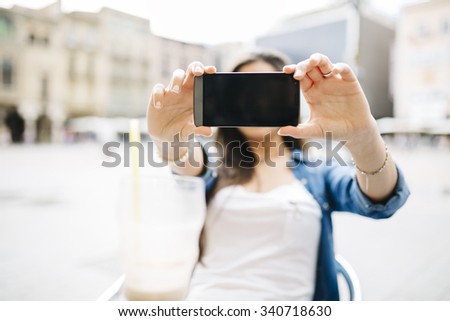 pretty young woman showing the screen of your mobile phone