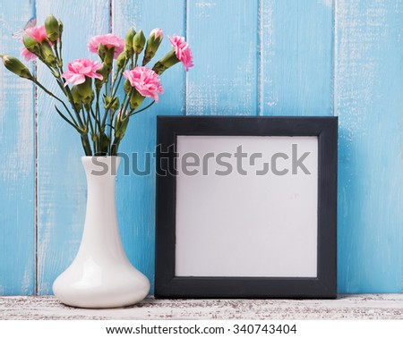 Blank frame and pink flowers in a vase.