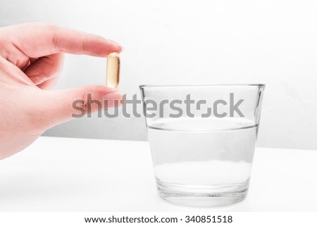 Omega 3 fish oil capsule hold with glass of water