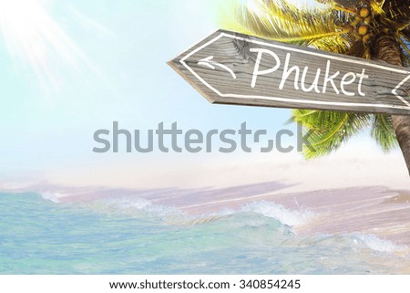 Phuket wooden sign and blurry exotic beach background. Tropical landscape with coconut palm tree and white sand beach. Paradise design banner background.