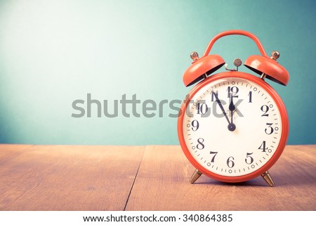 Retro alarm clock with five minutes to twelve o'clock. Old style filtered photo Royalty-Free Stock Photo #340864385