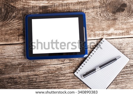 tablet and and notebook with pen on wood table