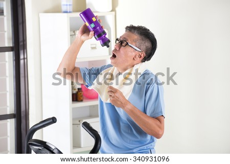 asian senior male drinking water on exercise bike