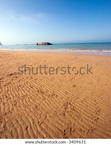 Color DSLR wide angle view of Mulberry Harbor, Normandy beach, France. Coast was used in WWII D-Day Invasion. Rippled sand in the foreground and English Chanel water and blue sky background. Vertical