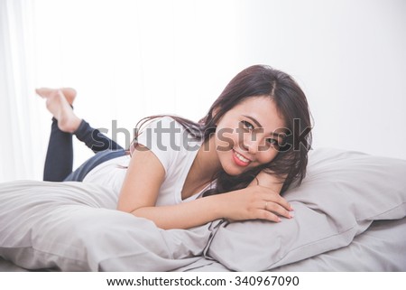Woman laying on the bed, resting her body looking at the camera