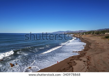 People on the beach, blue sky and sea, waves crashing at sunrise on Moonstone Beach next to Shamel Park and Santa Rosa Estuary, along Big Sur Coast, California Central Coast, near Cambria CA.