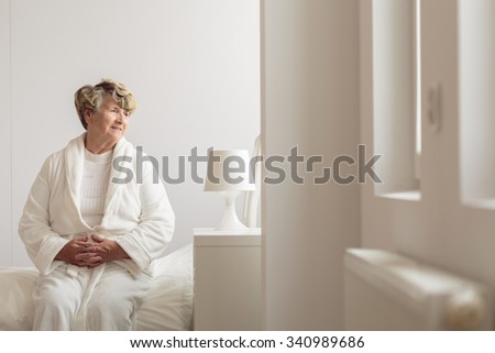 Photo of elderly female hospital patient sitting on bed Royalty-Free Stock Photo #340989686