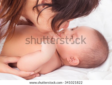 Young asian mother playing with her baby on white bed