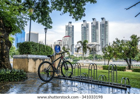 Bicycle parking rack in public park with modern building on background.