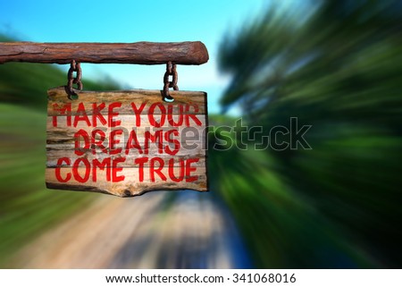 Make your dreams come true motivational phrase sign on old wood with blurred background