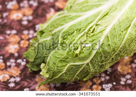 Closeup of fresh juicy ripe green foliage of chinese cabbage rustic ecological vegetable vegan food on floral dark background indoor, horizontal picture