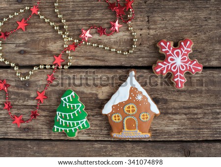 Homemade gingerbread cookies in the shape of house with snow, Christmas tree and snowflake on the wooden table. Space for text and selective focus.