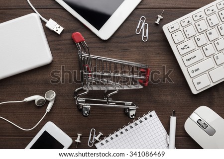 shopping online concept. small red trolley and gadgets on the table Royalty-Free Stock Photo #341086469