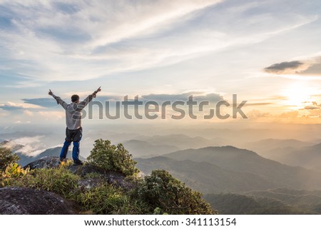 Tourist man spread hand on top of a mountain enjoying valley view Royalty-Free Stock Photo #341113154