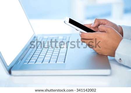 Cropped image of woman using smartphone at the desk in work