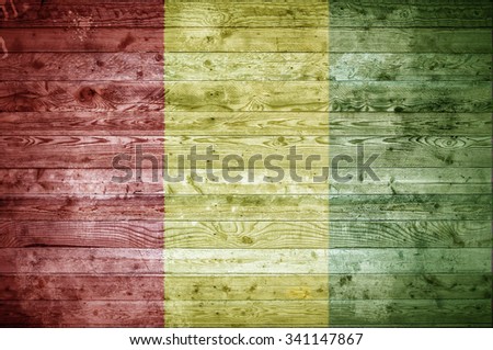 A vignetted background image of the flag of Guinea painted onto wooden boards of a wall or floor.