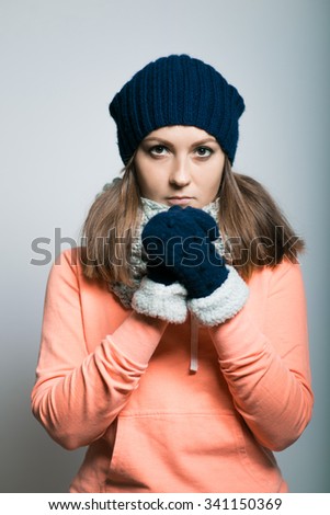 cute girl praying, dressed in winter clothes. hipster, isolated on a gray background