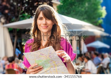 Young woman tourist holding a paper map in, Madrid, Spain, looking for direction.