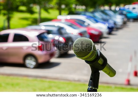 microphone on a stand with blurred vehicles in car park background, outdoor.