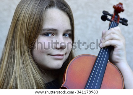 Beautiful teen girl playing on a wooden violin