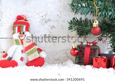 snowman sitting on the snow with christmas tree already decorated in vintage background