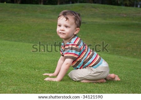 little two year old boy crawling on grass