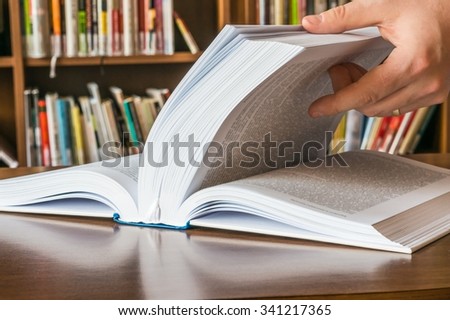 The hand of a man opening and browsing the book pages