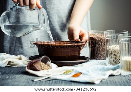 pouring water from a glass jug into a bowl, hands,cooking process Royalty-Free Stock Photo #341238692