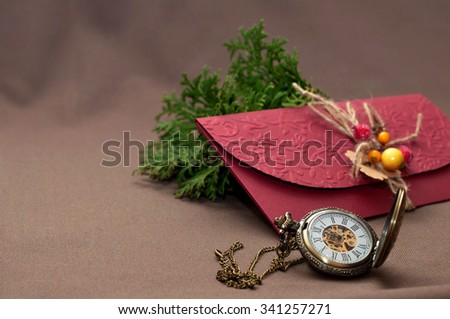 Purple envelope with the old watch on a brown surface