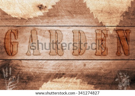 Word garden written, burned letters on wooden brown background.